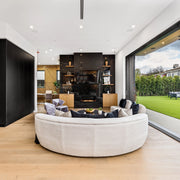 Modern living room with a curved white sofa, Empire Boulevard fireplace, and large windows.